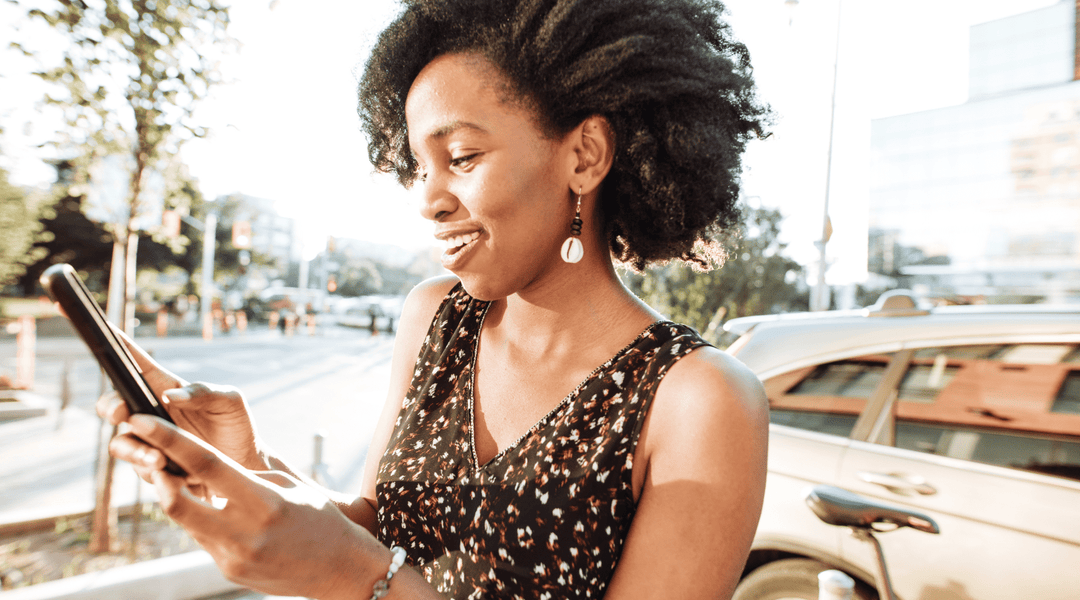 Black woman with Type 4 Hair reading about whipped shea butter on her phone for natural hair. 