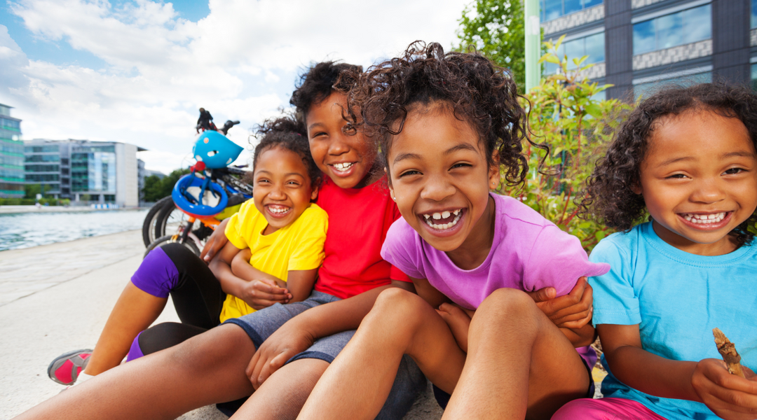 Four smiling children with radiant, healthy skin enjoying the outdoors. Discover the best natural eczema treatment to keep your child's skin soft and irritation-free.